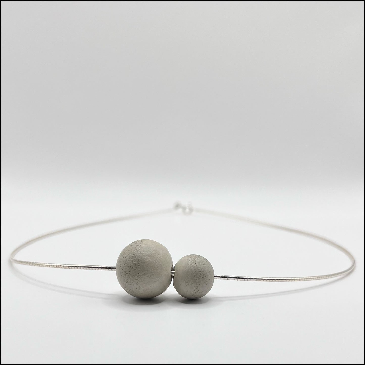 A minimalist concrete sphere pendant paired with a sleek 925 silver choker necklace.