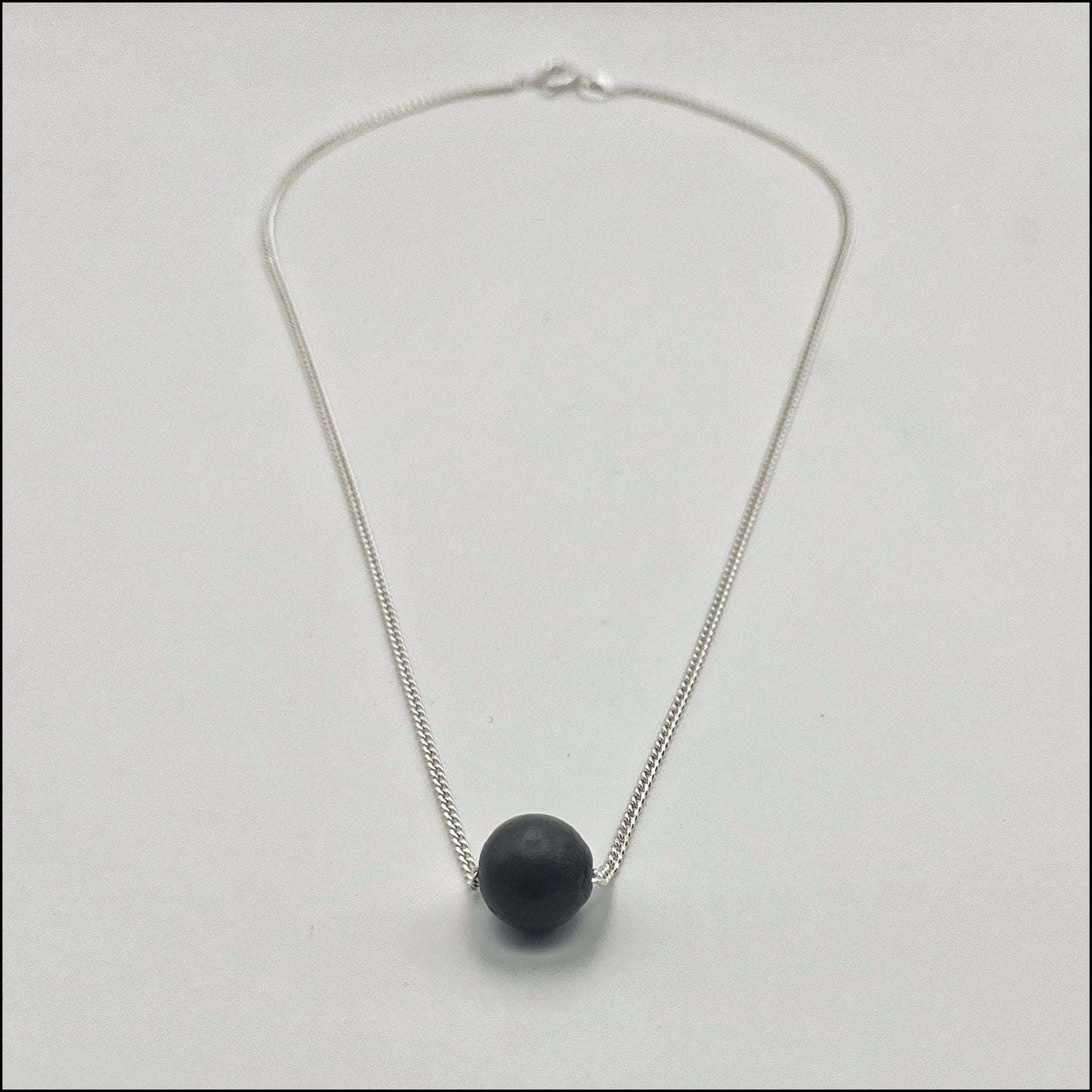 Necklace with a black sphere pendant on a light gray background