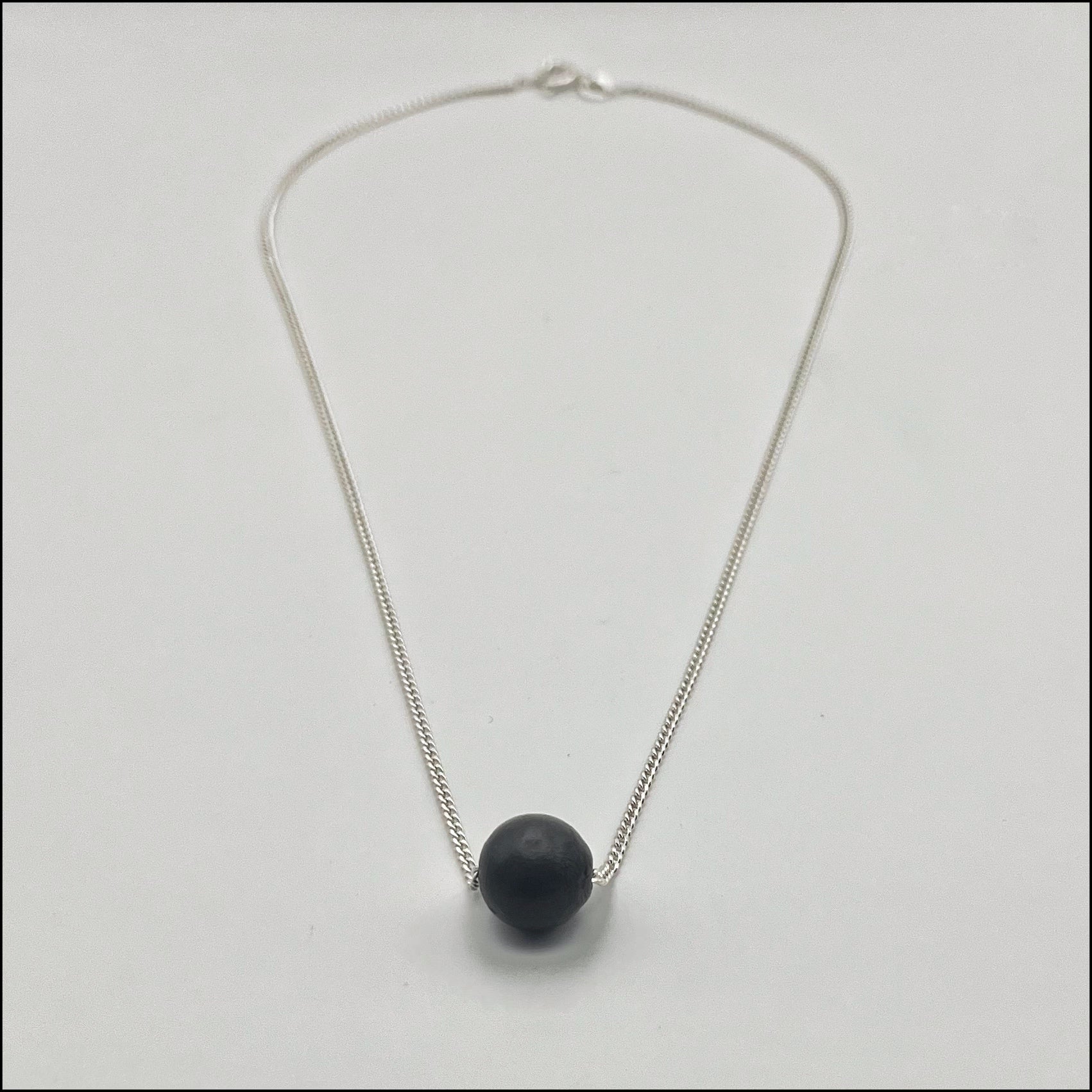 Necklace with a black sphere pendant on a light gray background
