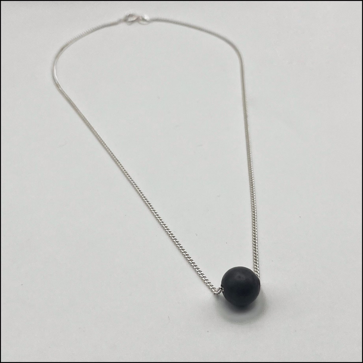 Necklace with a black pendant on a light gray background