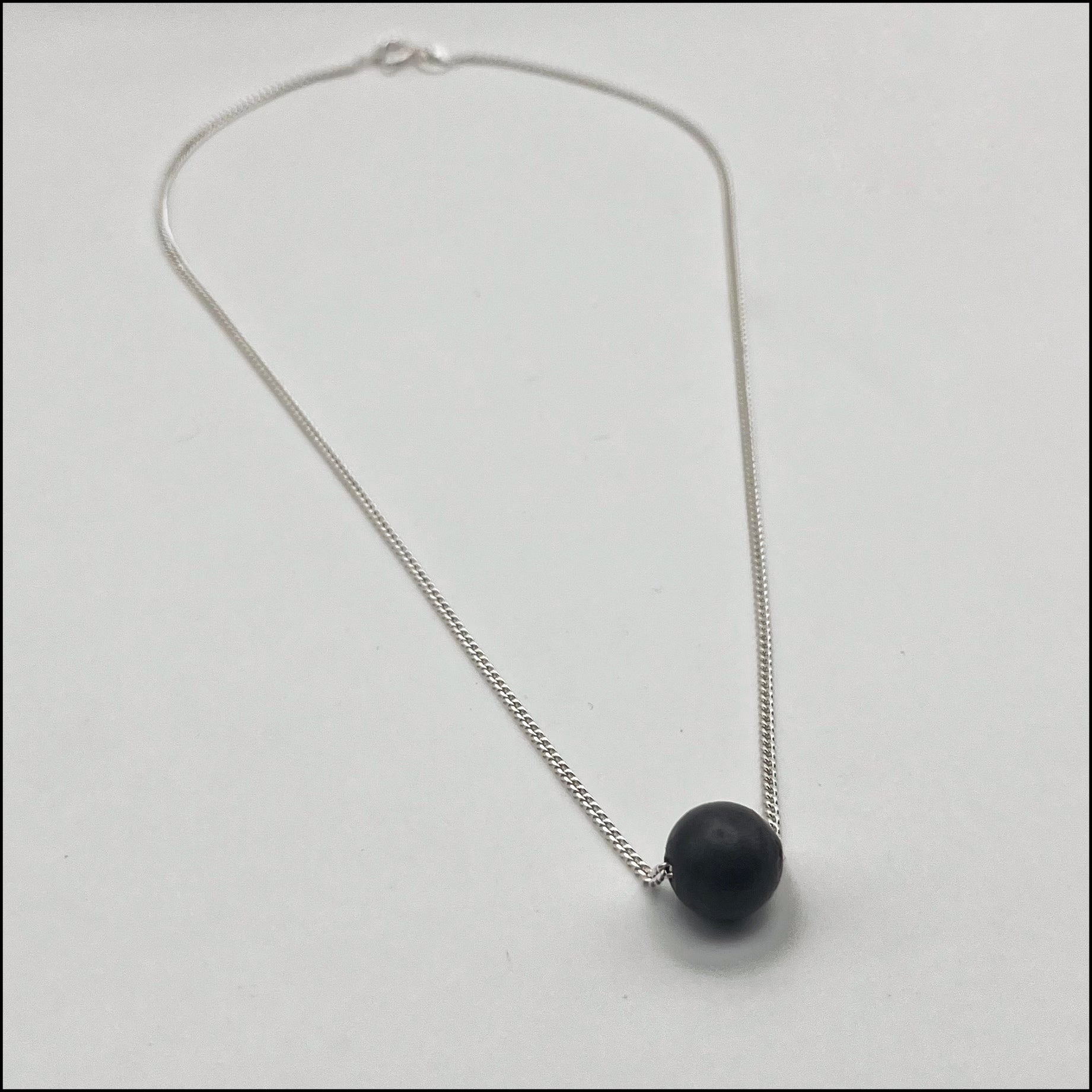 Necklace with a black pendant on a light gray background