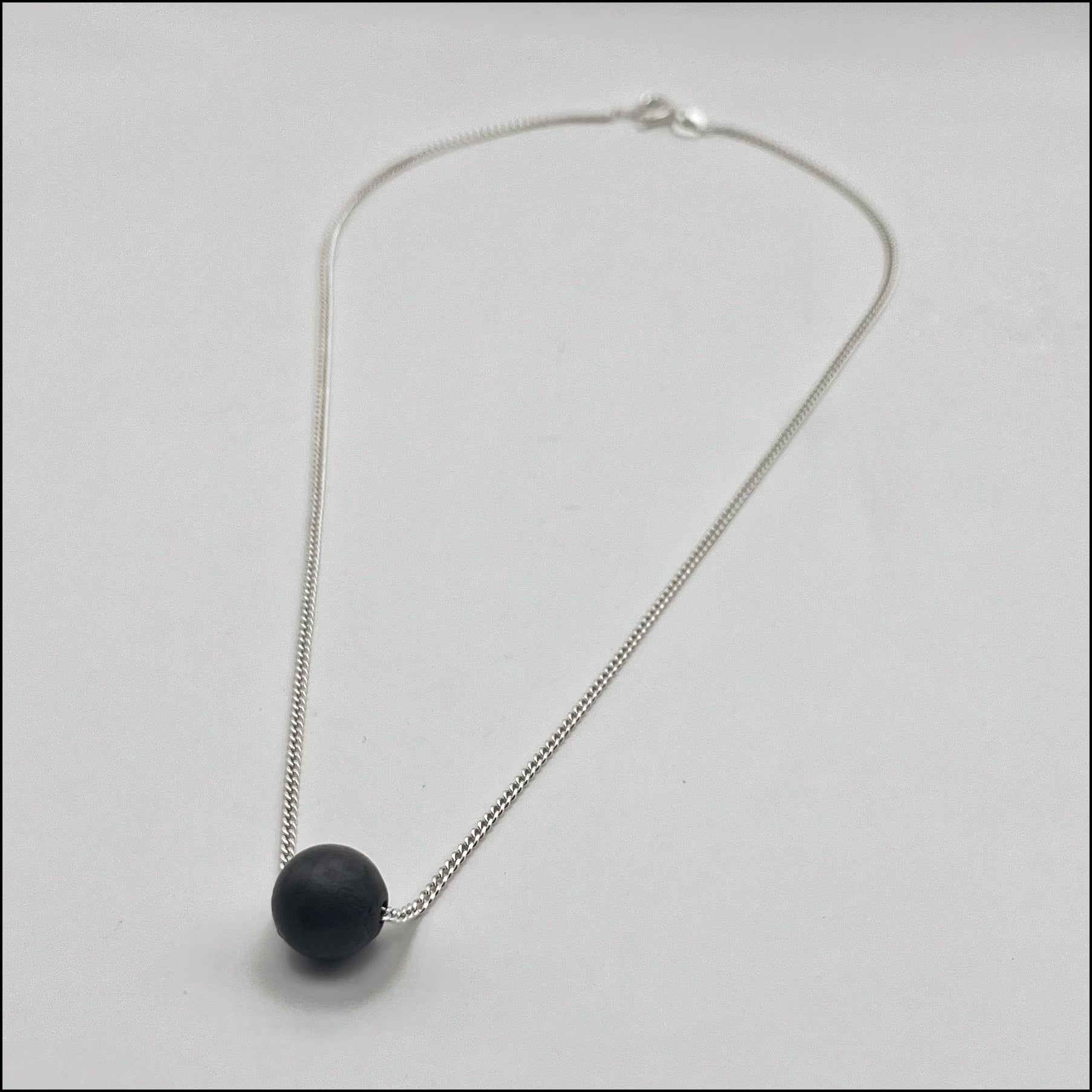 Necklace with a black pendant on a light gray background